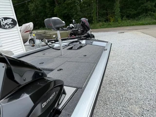 Slide: The Image of 2026 Vexus AVX181 boat on gravel, featuring spacious deck and motor, with trees in background. - 6