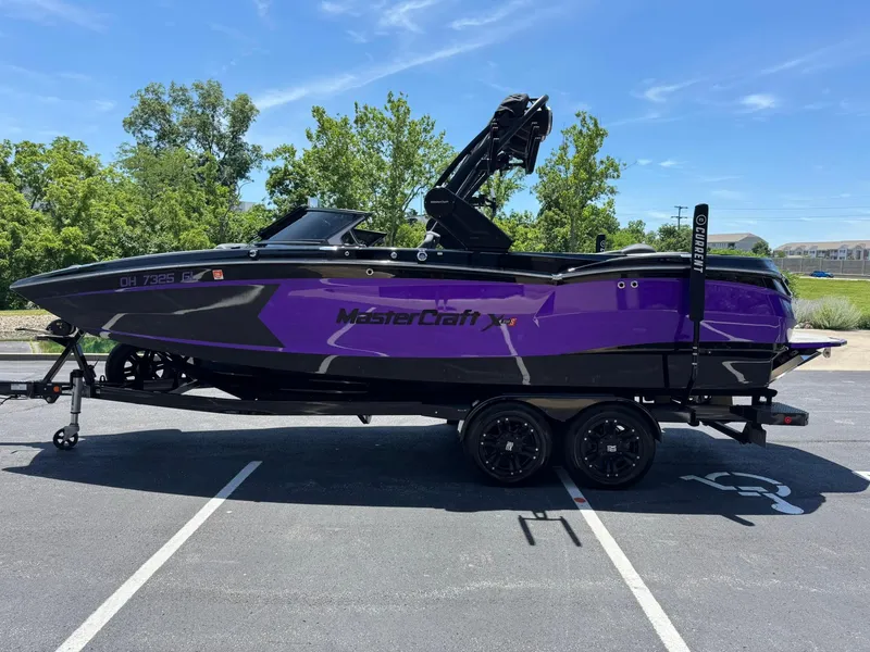 Slide: The Image of 2023 MasterCraft XStar S Piranha boat in purple and black on a trailer. - 22