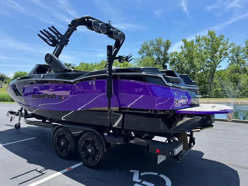 Slide: The Image of 2023 MasterCraft XStar S Piranha boat in vibrant purple, parked on a trailer. - 24