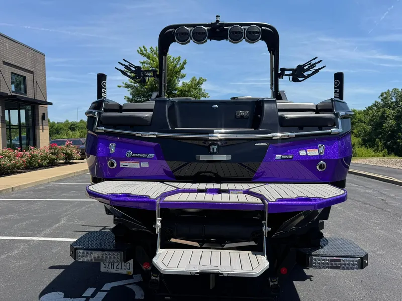 Slide: The Image of 2023 MasterCraft XStar S Piranha boat, rear view, vibrant purple finish, parked outdoors. - 26