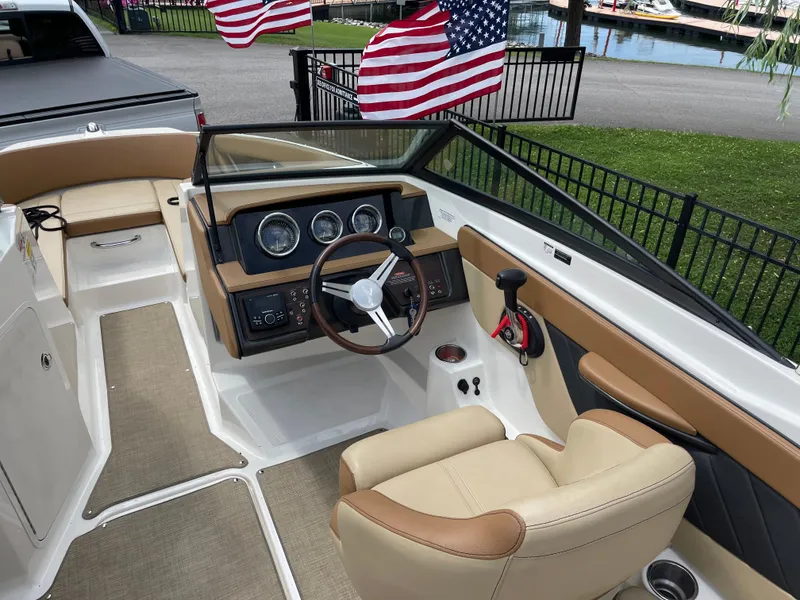 Slide: The Image of 2018 Sea Ray SPX 210 boat interior with steering wheel and dashboard, American flags in background. - 7