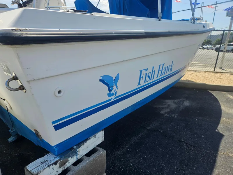 Slide: The Image of 1994 Celebrity Fish Hawk 18 boat with blue logo and stripes, parked on a stand. - 5