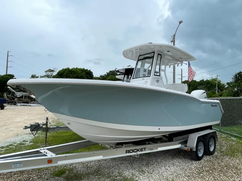 Slide: The Image of 2026 Tidewater 232 CC Adventure boat on trailer, parked outdoors under cloudy sky. - 1