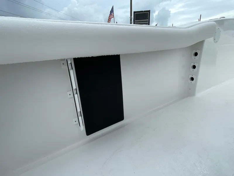 Slide: The Image of 2026 Tidewater 232 CC Adventure boat interior detail with rod holders and storage compartment. - 20