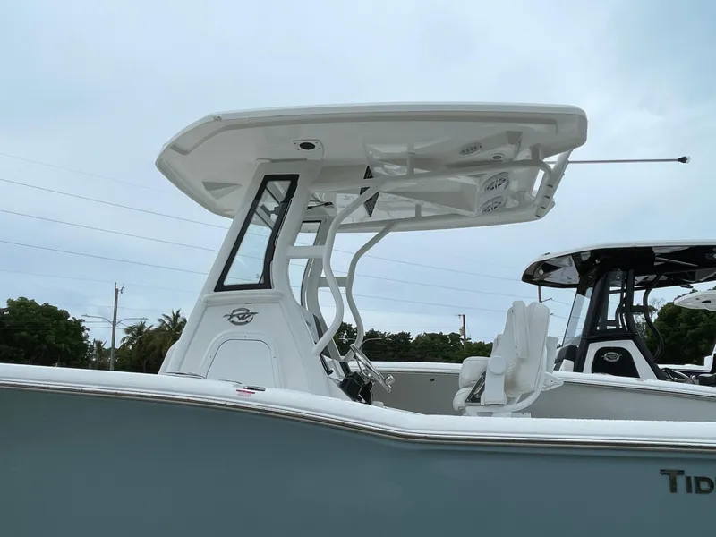 Slide: The Image of 2026 Tidewater 232 CC Adventure boat with T-top and seating, side view. - 3