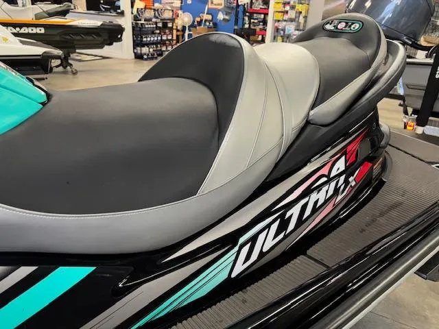 Slide: The Image of 2021 Kawasaki Ultra LX jet ski with sleek black and teal design in showroom. - 4