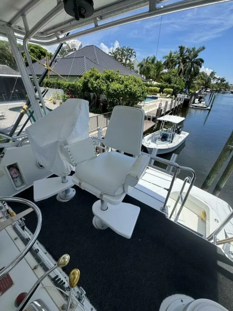 Slide: The Image of Captain's chair on 1989 Hatteras 42 Convertible yacht, docked by a scenic waterfront. - 19