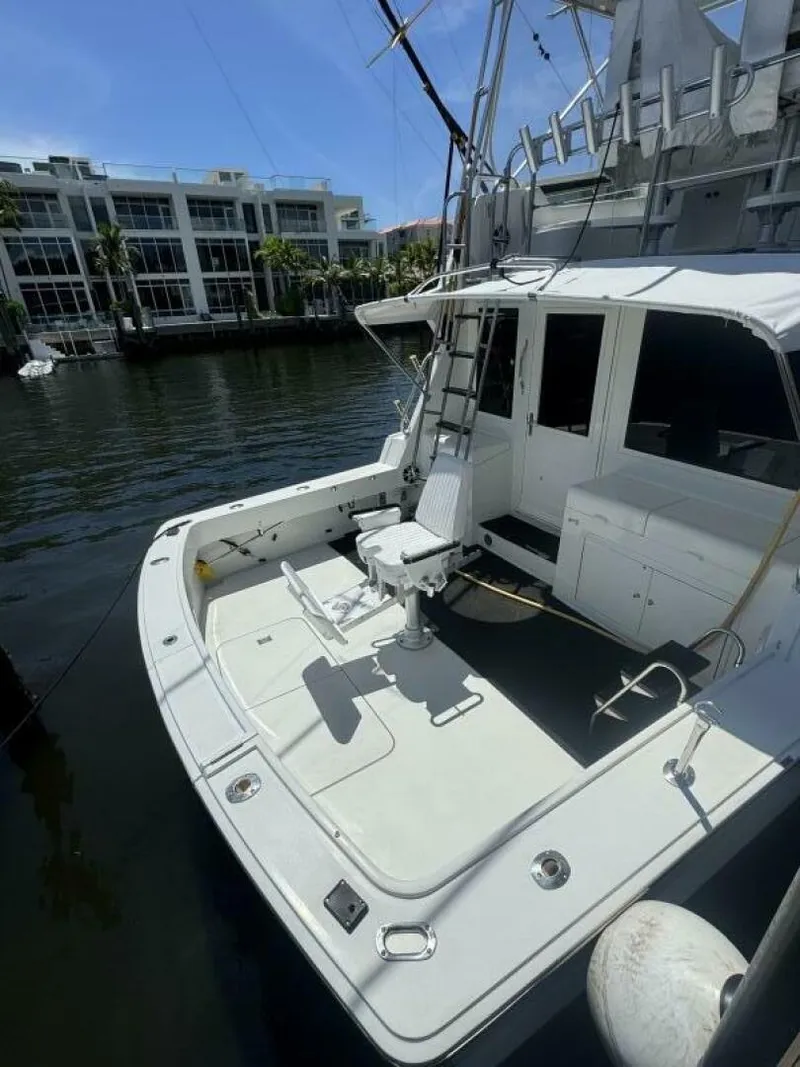 Slide: The Image of 1989 Hatteras 42 Convertible yacht docked, featuring spacious deck and fishing chair. - 4