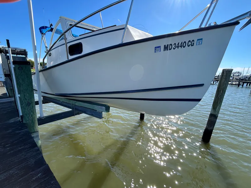 Slide: The Image of 2014 Seaway 21 Seafarer Cuddy boat on lift, docked by sunny waterfront. - 3