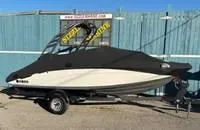 Slide: The Image of 2020 Yamaha Boats 195S covered on trailer, parked by a blue fence. - 30