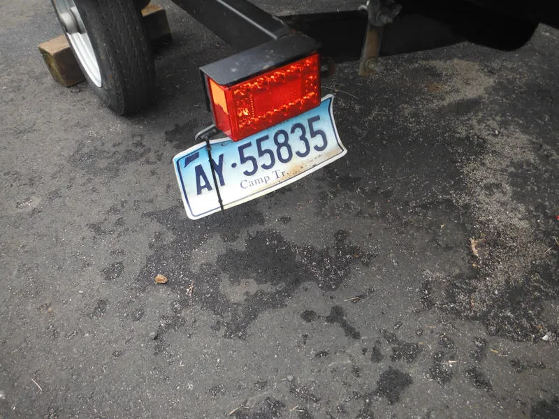 Slide: The Image of Trailer with bent license plate and red reflector light on asphalt. - 33