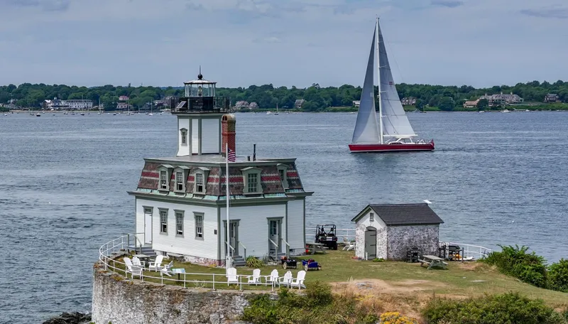Slide: The Image of Sailboat Nautor Swan 100 Pilothouse near historic lighthouse on a scenic coastal landscape. - 14