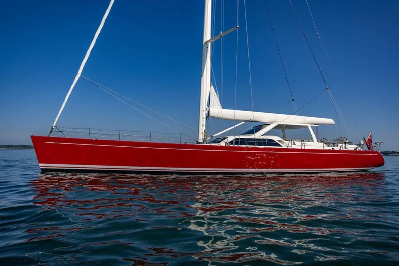 Slide: The Image of Red Nautor Swan 100 Pilothouse yacht from 2003 on calm water under clear blue sky. - 4