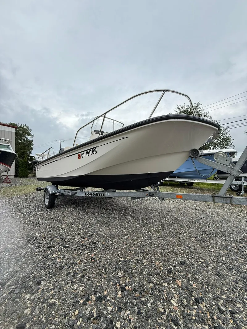 Slide: The Image of 2019 Boston Whaler 150 Montauk boat on trailer, parked on gravel lot. - 13