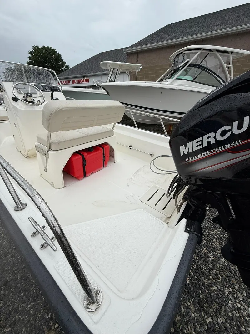 Slide: The Image of 2019 Boston Whaler 150 Montauk boat with Mercury FourStroke engine, docked outdoors. - 8