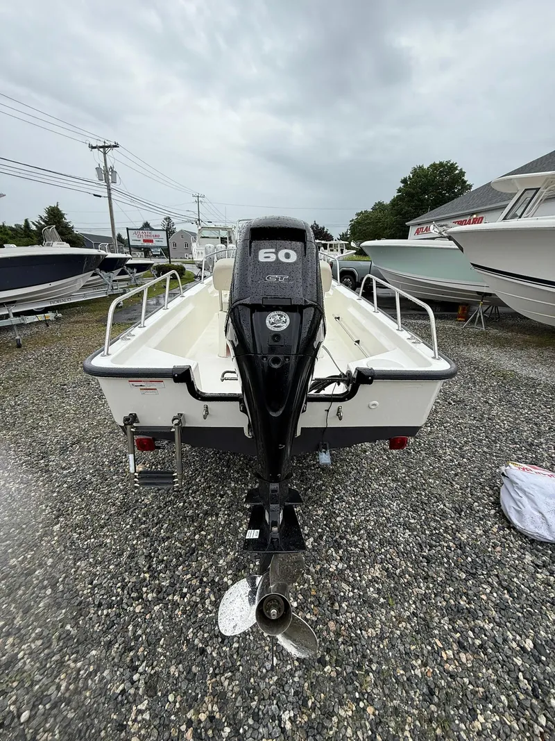 Slide: The Image of 2019 Boston Whaler 150 Montauk boat with 60 HP engine, displayed on gravel lot. - 9