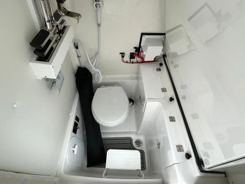 Slide: The Image of 2026 Tidewater 256 CC Adventure boat interior with compact marine toilet and storage. - 15