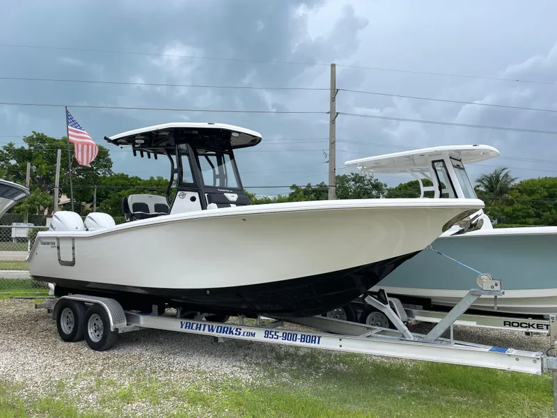 Slide: The Image of 2026 Tidewater 256 CC Adventure boat on trailer, displayed outdoors with American flag. - 2