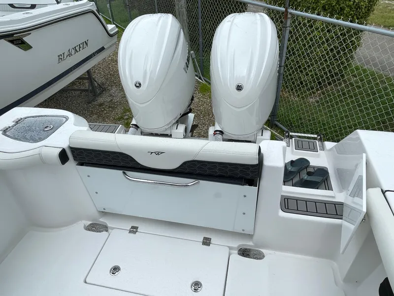 Slide: The Image of 2026 Tidewater 256 CC Adventure boat with dual outboard engines, docked near a fence. - 30