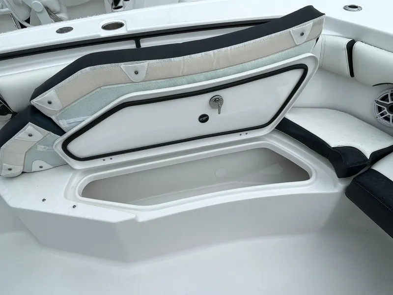 Slide: The Image of 2026 Tidewater 256 CC Adventure boat with open storage compartment and cushioned seating. - 6