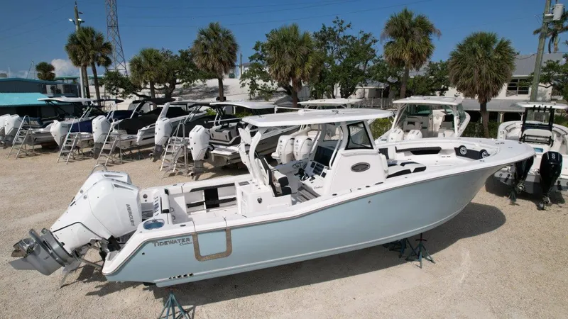 Slide: The Image of 2025 Tidewater 320 CC Adventure boat with Mercury outboard engine, parked outdoors. - 4