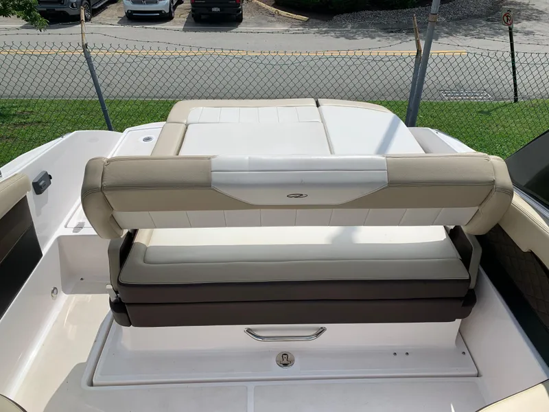 Slide: The Image of 2014 Regal 27 FasDeck boat with beige and white seating, parked near a fence. - 13