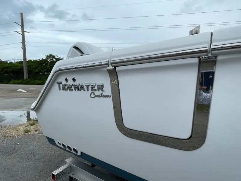 Slide: The Image of 2026 Tidewater 282 CC Adventure boat, white exterior with custom detailing, parked outdoors. - 23