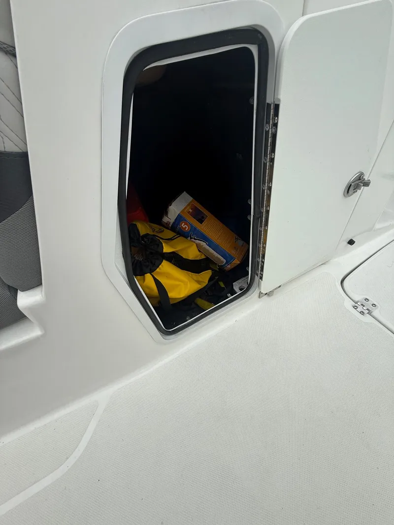 Slide: The Image of Open storage compartment on 2022 Hurricane SD 2486 boat, containing various items. - 10