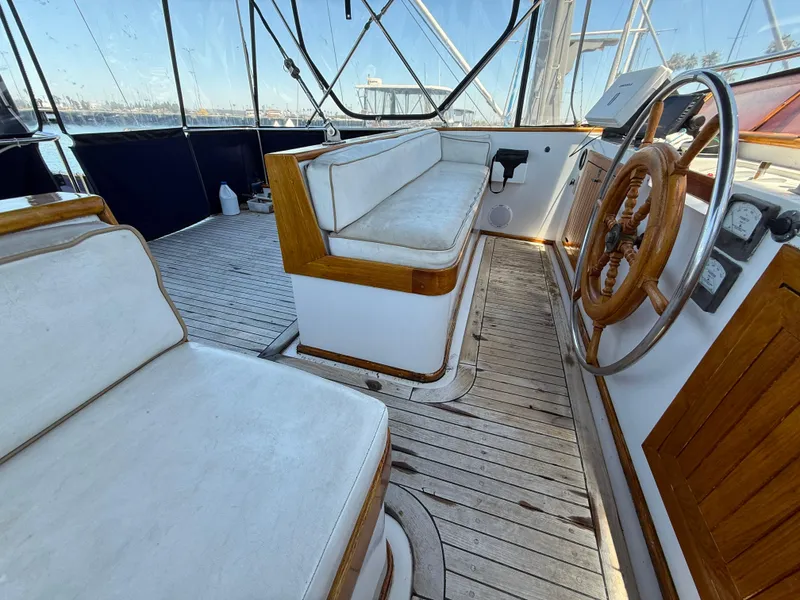 Slide: The Image of 1981 DeFever Passagemaker helm with wooden wheel and cushioned seating. - 11