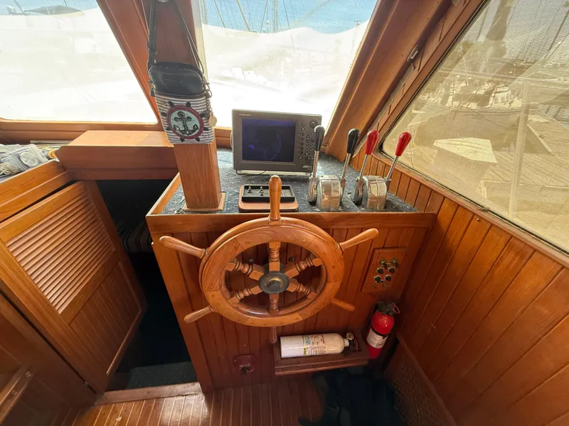 Slide: The Image of 1981 DeFever Passagemaker helm with wooden wheel, navigation equipment, and control levers. - 14