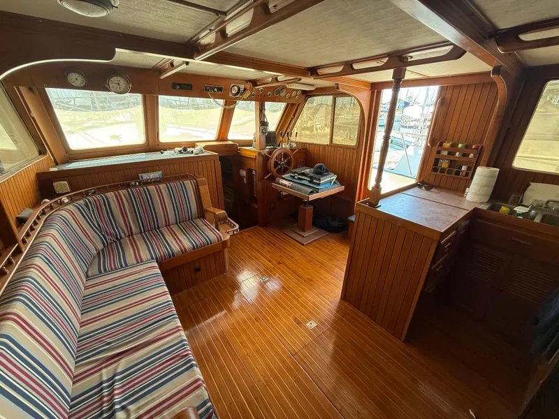 Slide: The Image of 1981 DeFever Passagemaker interior with striped seating, wooden helm, and nautical decor. - 17