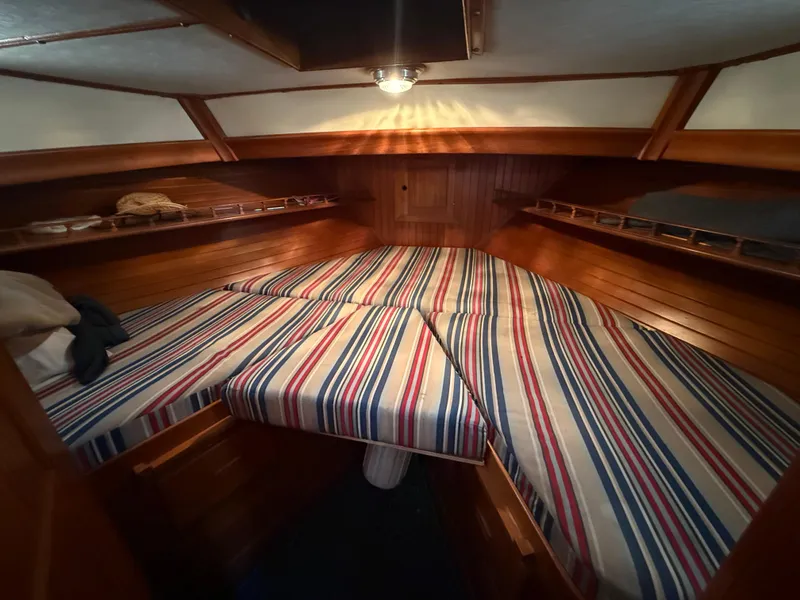 Slide: The Image of 1981 DeFever Passagemaker cabin with striped bedding and wooden interior. - 18