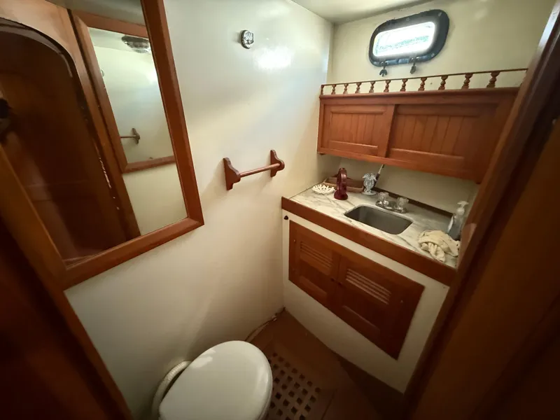 Slide: The Image of 1981 DeFever Passagemaker bathroom with wooden cabinets, sink, and porthole window. - 19