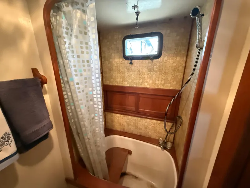 Slide: The Image of 1981 DeFever Passagemaker bathroom with shower, wooden accents, and porthole window. - 24