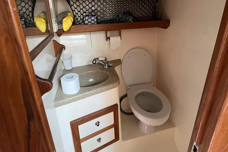 Slide: The Image of 2004 Albemarle 310 Express Fisherman boat bathroom with sink, toilet, and storage shelves. - 11