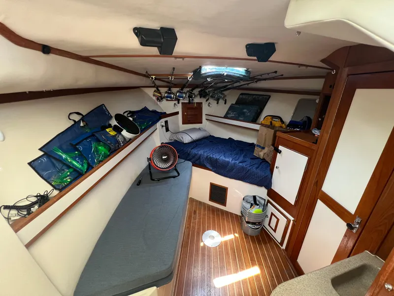 Slide: The Image of 2004 Albemarle 310 Express Fisherman cabin interior with bed, fishing rods, and storage. - 7
