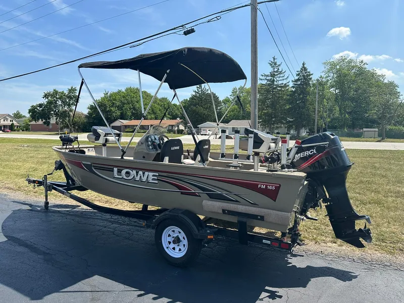 Slide: The Image of 2007 Lowe Fishing Machine FM165S boat on trailer, parked outdoors under clear sky. - 5
