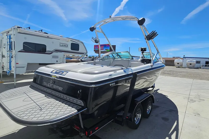 Slide: The Image of 2007 Supreme V232 boat on trailer, parked near RVs under clear blue sky. - 22