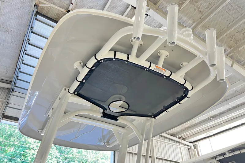 Slide: The Image of 2026 Boston Whaler 220 Dauntless T-top with rod holders in a warehouse setting. - 8