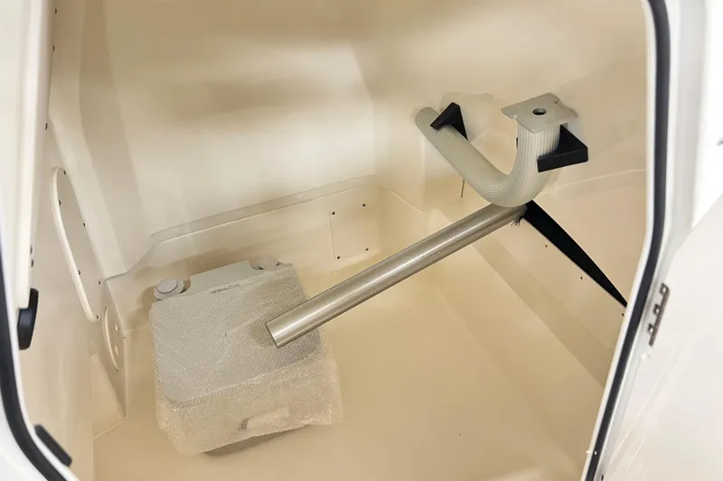 Slide: The Image of 2026 Boston Whaler 220 Dauntless interior storage compartment with wrapped equipment and metal support. - 9