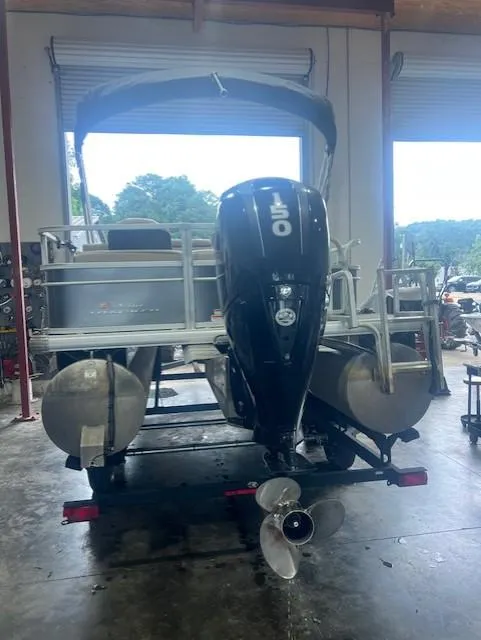 Slide: The Image of 2018 Tracker 22 DLX pontoon boat with 150 HP engine in a garage setting. - 3