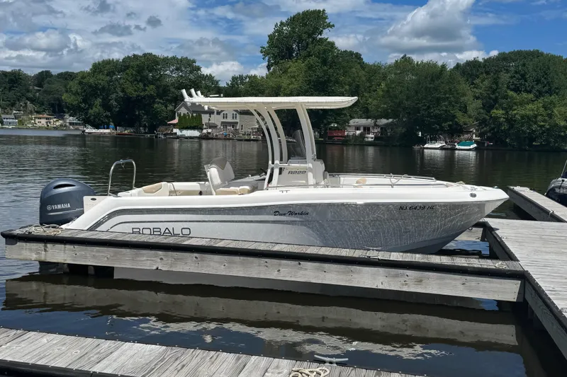 The Image of 2018 Robalo R222 Explorer boat docked on a calm lake with scenic background. - 0