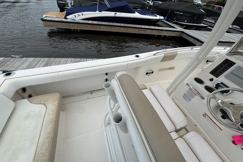 Slide: The Image of 2018 Robalo R222 Explorer boat interior with seating and steering wheel, docked by the water. - 11