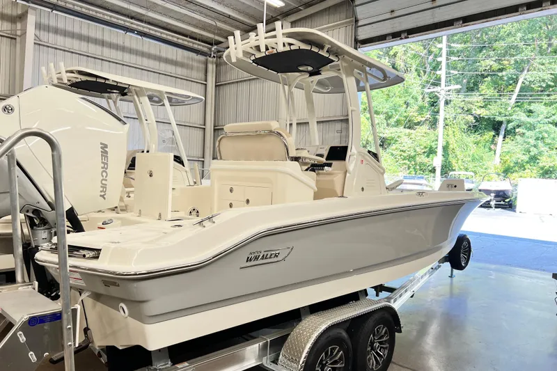 Slide: The Image of 2026 Boston Whaler 250 Dauntless boat in showroom, featuring sleek design and Mercury engine. - 2
