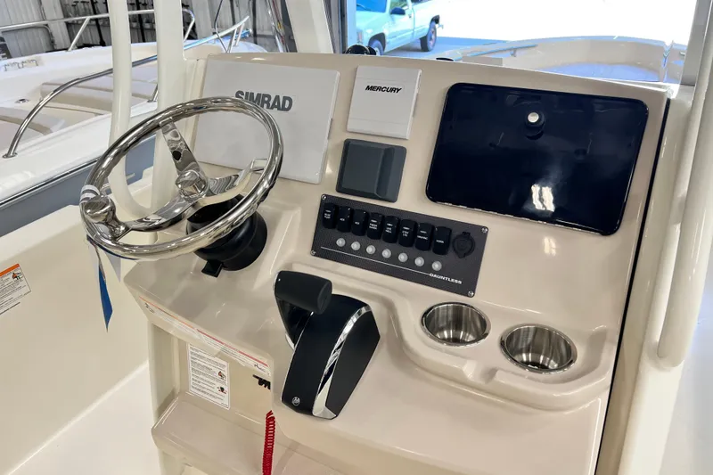 Slide: The Image of 2026 Boston Whaler 250 Dauntless helm with steering wheel, controls, and cup holders. - 6
