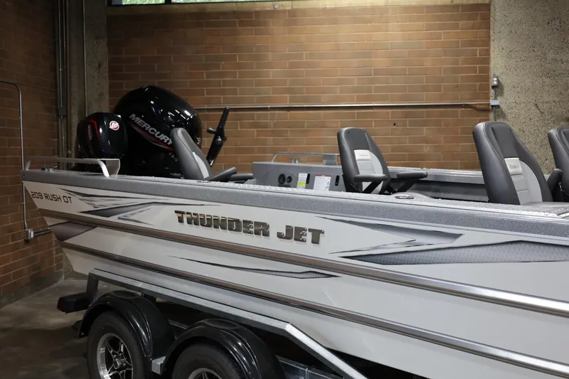 Slide: The Image of 2025 Thunder Jet 209 Rush OT boat with Mercury engine in a garage setting. - 2