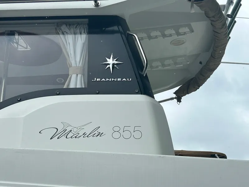 Slide: The Image of 2015 Jeanneau Merry Fisher 855 Marlin boat exterior with logo and window details. - 1