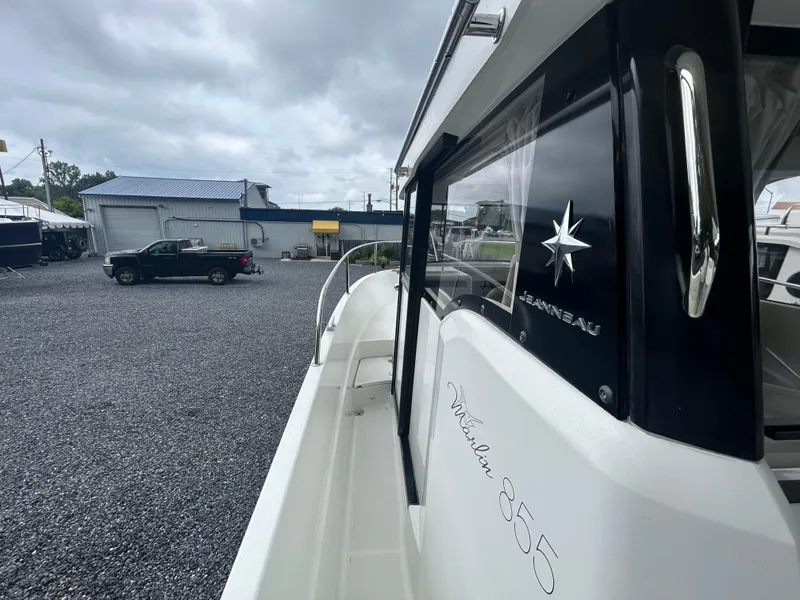 Slide: The Image of 2015 Jeanneau Merry Fisher 855 Marlin boat in a gravel lot, overcast sky. - 4
