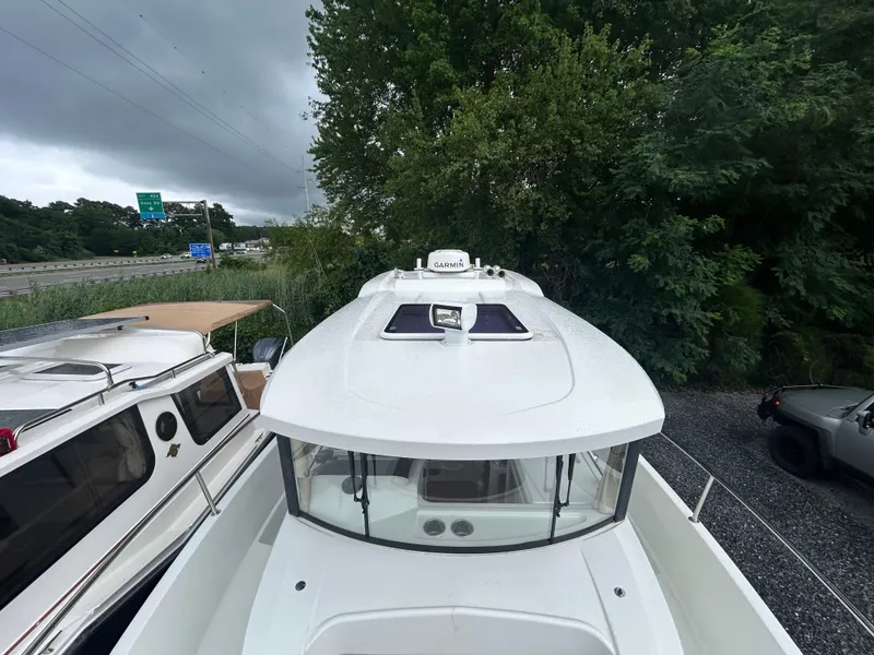 Slide: The Image of 2015 Jeanneau Merry Fisher 855 Marlin boat docked near trees and highway. - 6
