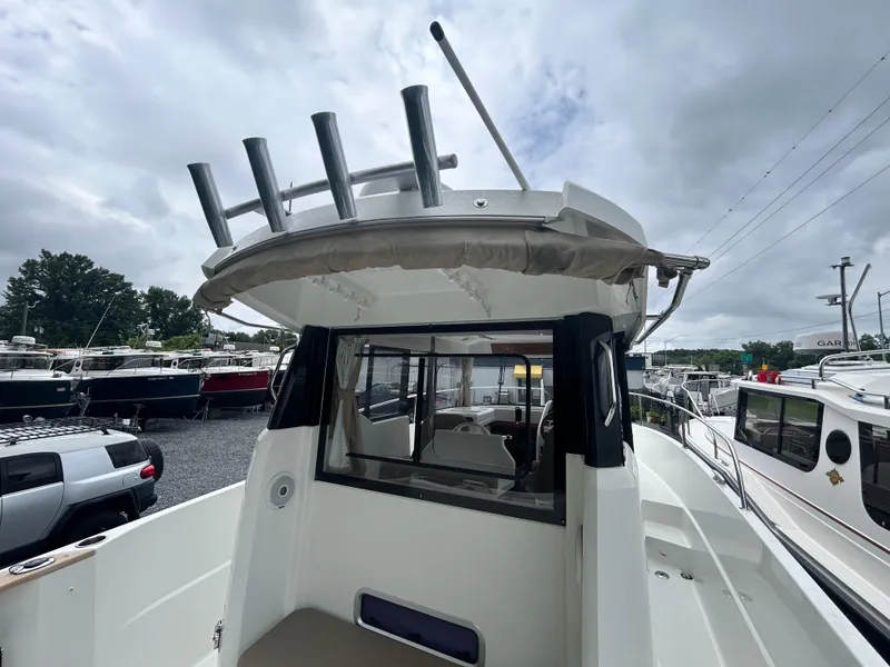 Slide: The Image of 2015 Jeanneau Merry Fisher 855 Marlin boat docked, showcasing rear deck and fishing rod holders. - 8